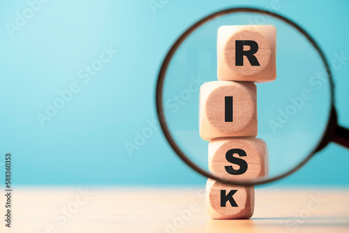 Risk wording print screen on wooden block cube and focus on magnifier glass for financial banking risk analysis and management ,Risk and return concept. photo