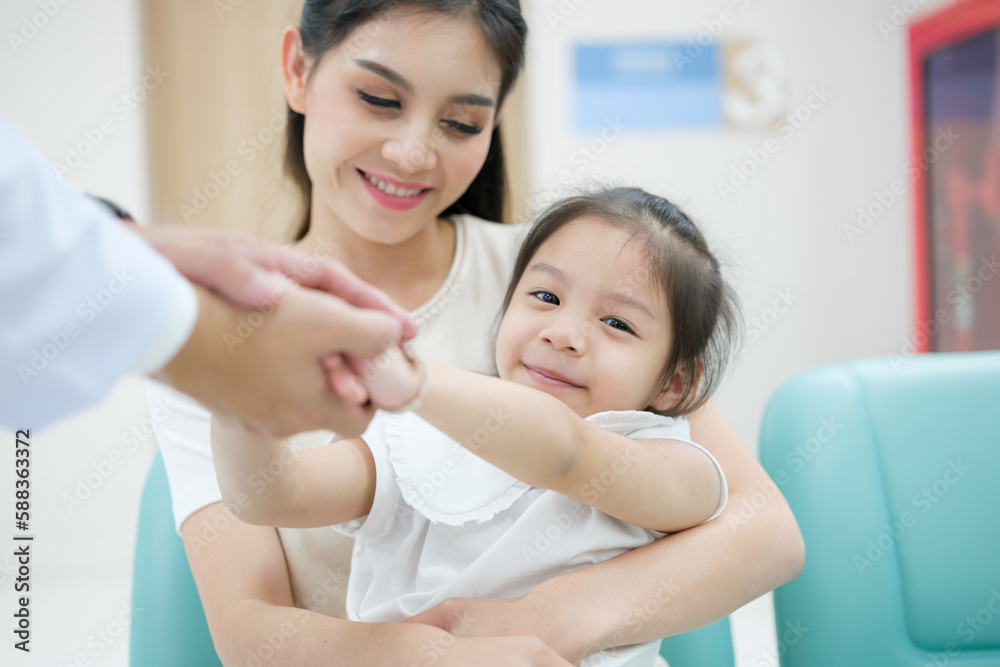 Fototapeta premium The doctor held the young patient's hand, and the mother smiled and encouraged her.