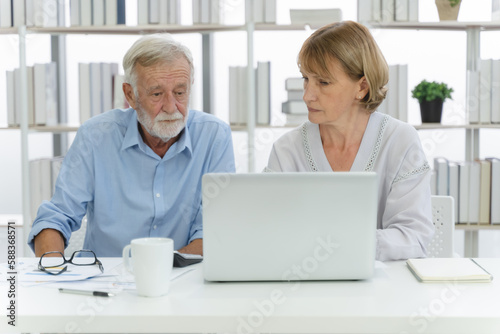 Mature couple looking at finance document and data on laptop computer and having a money problems