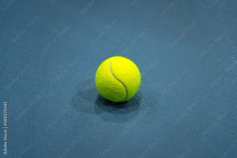 A flat lay close-up photo of the yellow tennis ball on blue background or tennis court.