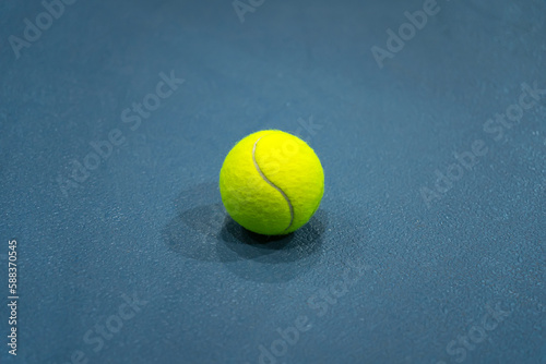 A flat lay close-up photo of the yellow tennis ball on blue background or tennis court. © diy13