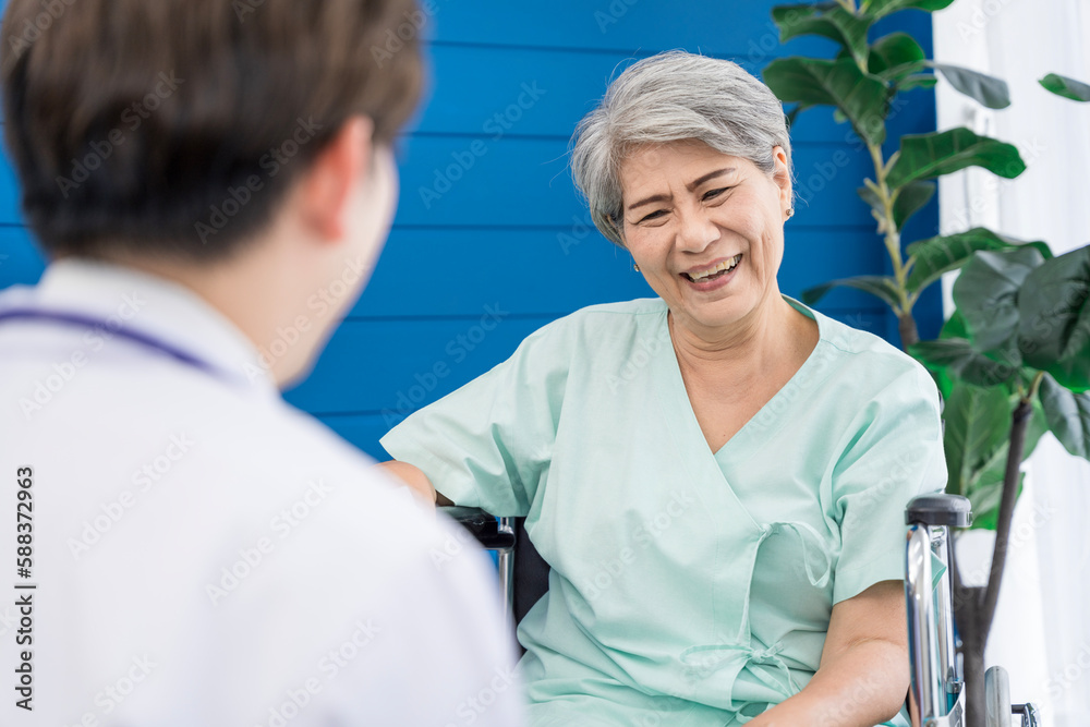 Obraz premium A doctor is caring for an elderly female patient at a hospital where she has undergone knee surgery. This made her need to use a wheelchair instead of walking and have a doctor take care of it closely
