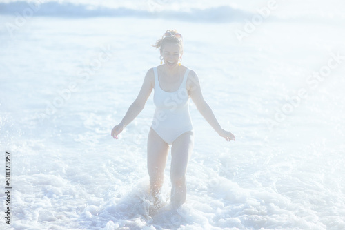 smiling modern woman in white swimwear at beach having fun time