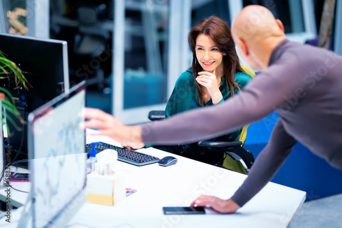 Group of business people sitting and standing together at the office surrounded computers and working together photo