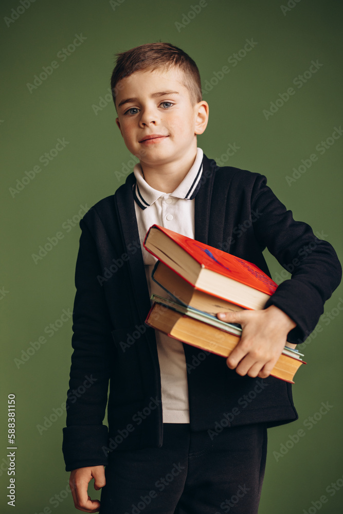Cute school boy wearing school uniform and holding books Cute school boy wearing school uniform and holding books