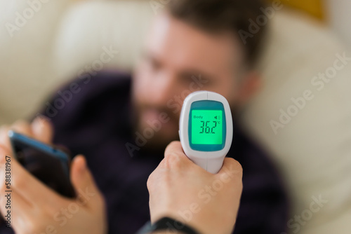 Close up of infrared digital forehead thermometer in hand,fever examination and measures to prevent and screen people check body temperature during its reopening after COVID-19 Coronavirus Lockdown