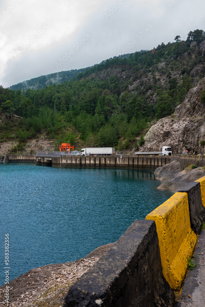 Fototapeta premium Beautiful and dangerous road, median and mountain by the lake
