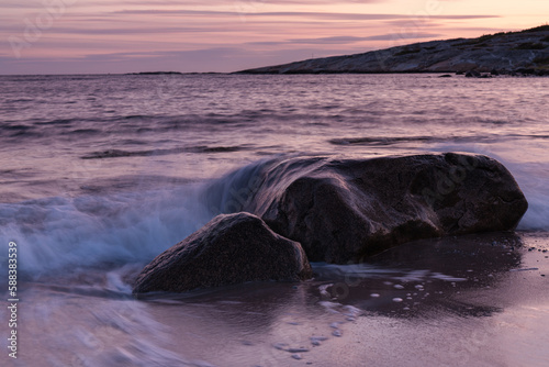 Sea coast  waves crashing against a stone in the water  sunset