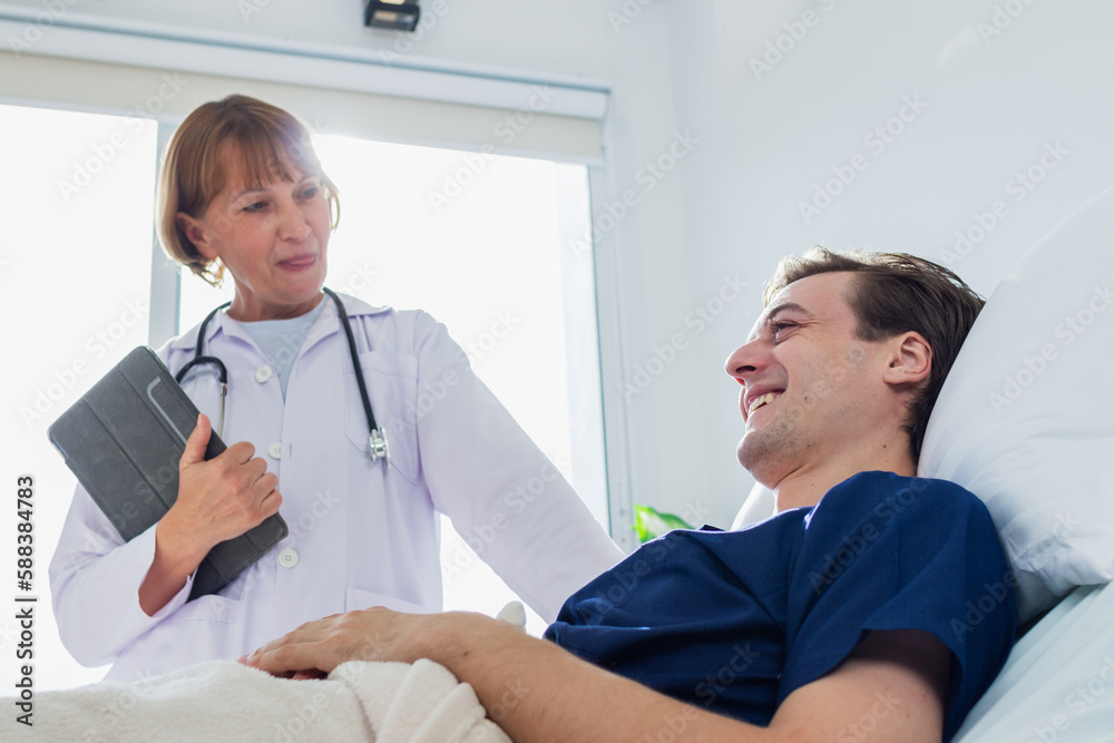 the doctor is examining the patient in the hospital. Caucasian female doctor talking to male patient lying in hospital bed. the doctor is examining the patient in the hospital. Caucasian female doctor talking to male patient lying in hospital bed.