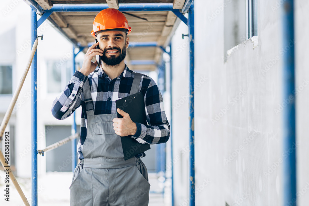 Foreman walking at the building object and talking on the phone Foreman walking at the building object and talking on the phone