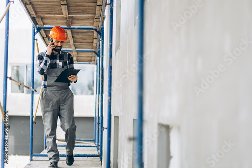 Foreman walking at the building object and talking on the phone