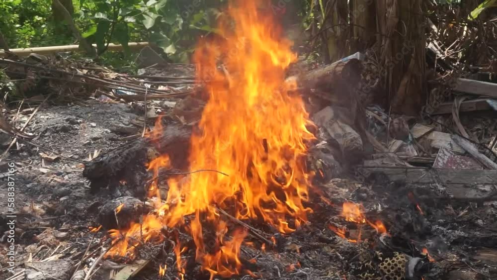 Burning trash on the ground. Flames at the junkyard. Pollution concept. Burning trash on the ground. Flames at the junkyard. Pollution concept.