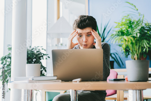 Middle aged shocked business woman sitting in front of laptop looking at screen at her workstation in office. Frustrated worried face expression emotion feelings problem perception reaction