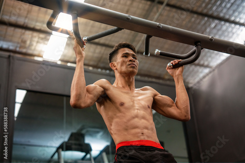 Filipino male boxer exercising with bra, weightlifting, building arm muscles in sports club © Supavadee