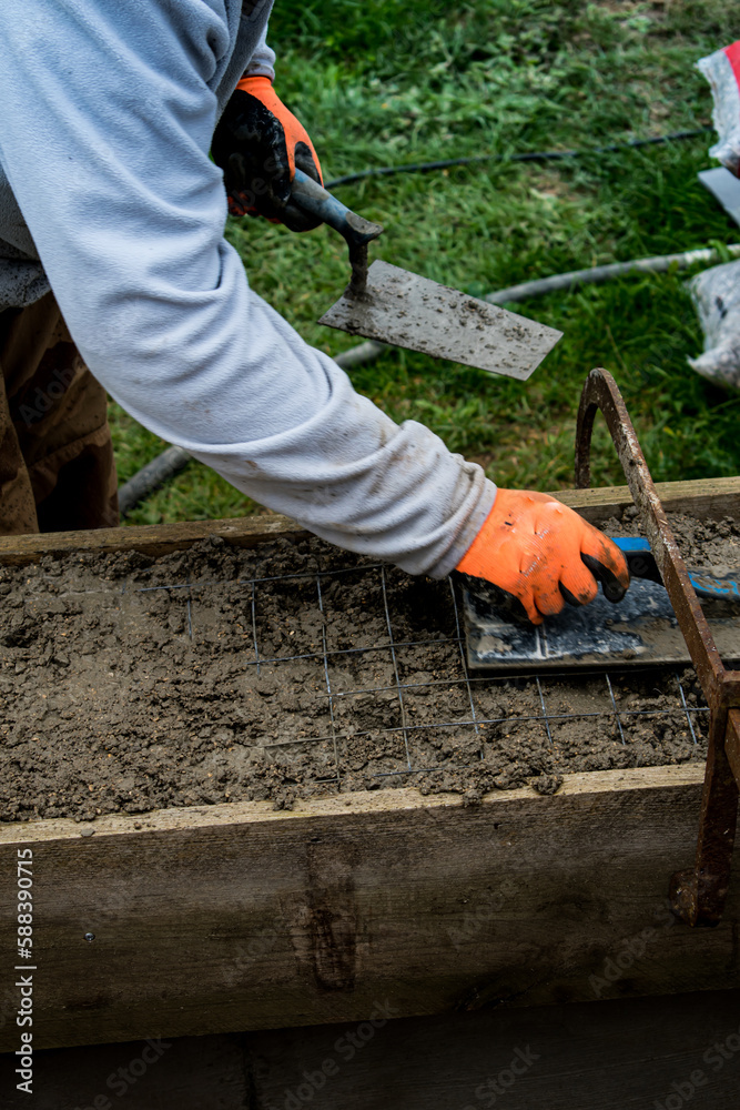 bricklayer-spreading-concrete-with-a-trowel-and-level-to-build-a-wall