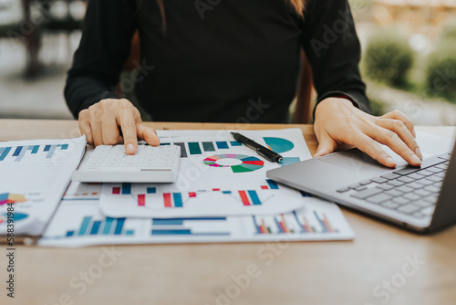 Working of businesswoman or accountant working on laptop computer analyzing business report graphs and financial charts in workplace concept of finance and investment