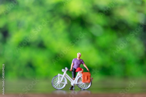 Miniature people standing with bike and green background , World bicycle day concept