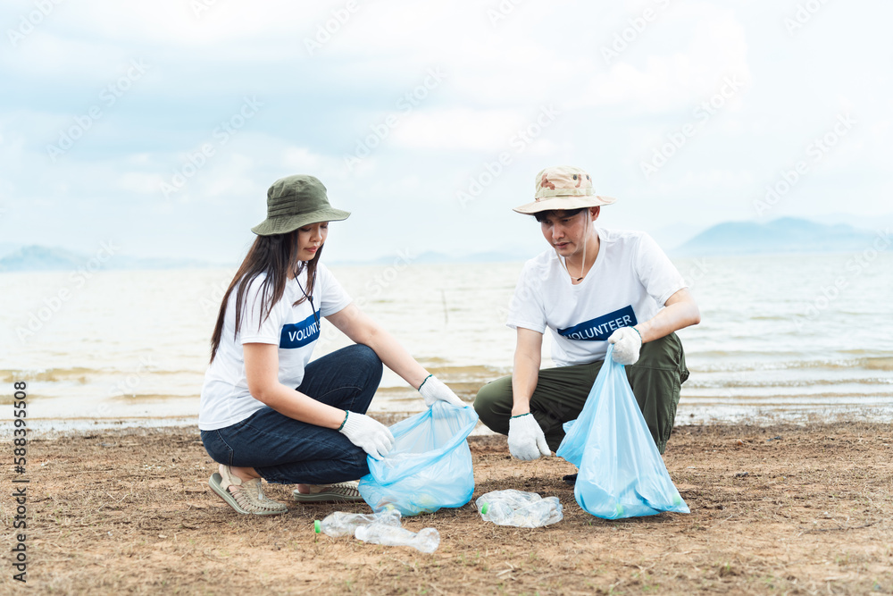 Young adult asian couple help to cleaning up plastic and foam garbage on river side area, Unity and team spirit on world environment day.
