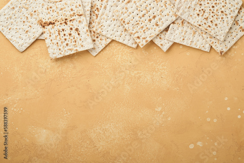 Passover Pesah celebration concept. Matzah, kosher red wine, walnut and white and yellow roses. Traditional ritual Jewish bread on sand color old tile wall background. Pesach Jewish holiday. Top view
