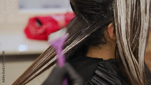 Dark haired woman getting hair coloured in a beauty salon highlighting procedure. High quality 4k footage