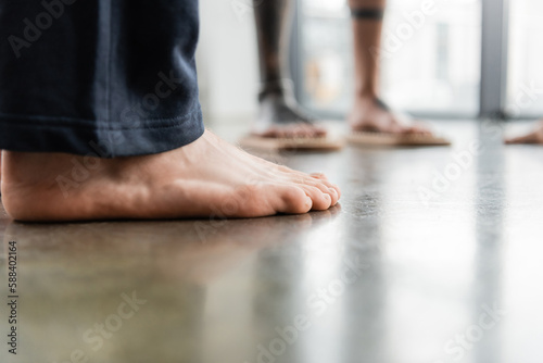 cropped view of man with bare feet standing in yoga studio.