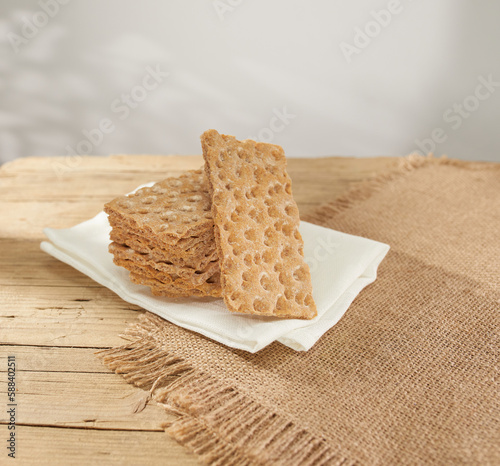 brown crispbreads on a wooden board and rough cloth. healthy snack with cereal bread. breakfast on a sunny day. crispy breadcrumbs ready for stuffing. food in rustic style. meal in country.