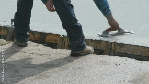 workman smoothing concrete on a newly poured street