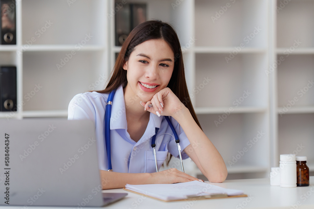 Smiling Happy and Beautiful Doctor working on laptop at clinic, health care, medical, healthy concept Smiling Happy and Beautiful Doctor working on laptop at clinic, health care, medical, healthy concept