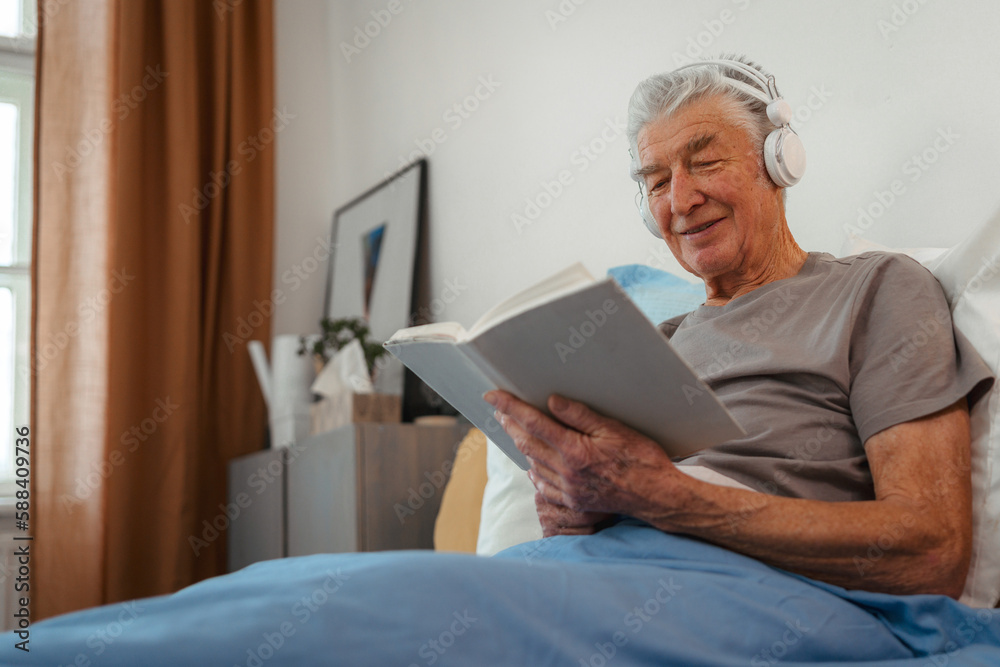 Senior man relaxing in his bed, learning book and listening music. Senior man relaxing in his bed, learning book and listening music.