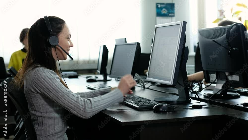 Operator of service center at workplace at computer receives call from client, puts on headset and begins to answer questions. Online service assistance. girl works in call center
