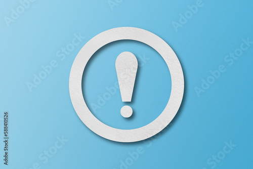 White paper punched into the shape of an exclamation mark. warning sign Set on a light blue paper background.