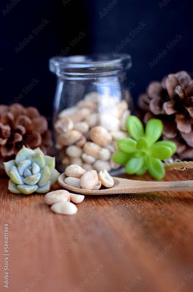 Peanut in jar with wooden and black background. Vertical