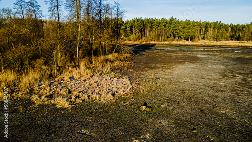 Aerial view of the fish pond with drained water and a river flowing on a sunny,winter day.