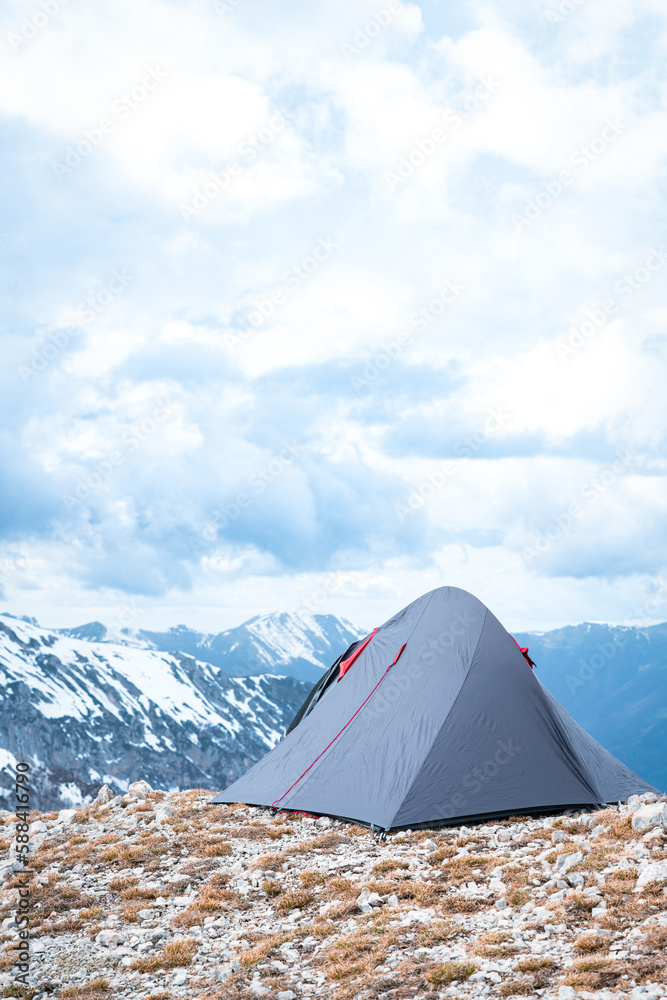 (Selective focus) Stunning view of a camping tent placed on the top of Monte Pratillo with snowcapped mountains in the distance, Prato di Campoli, Veroli, Frosinone, Italy.