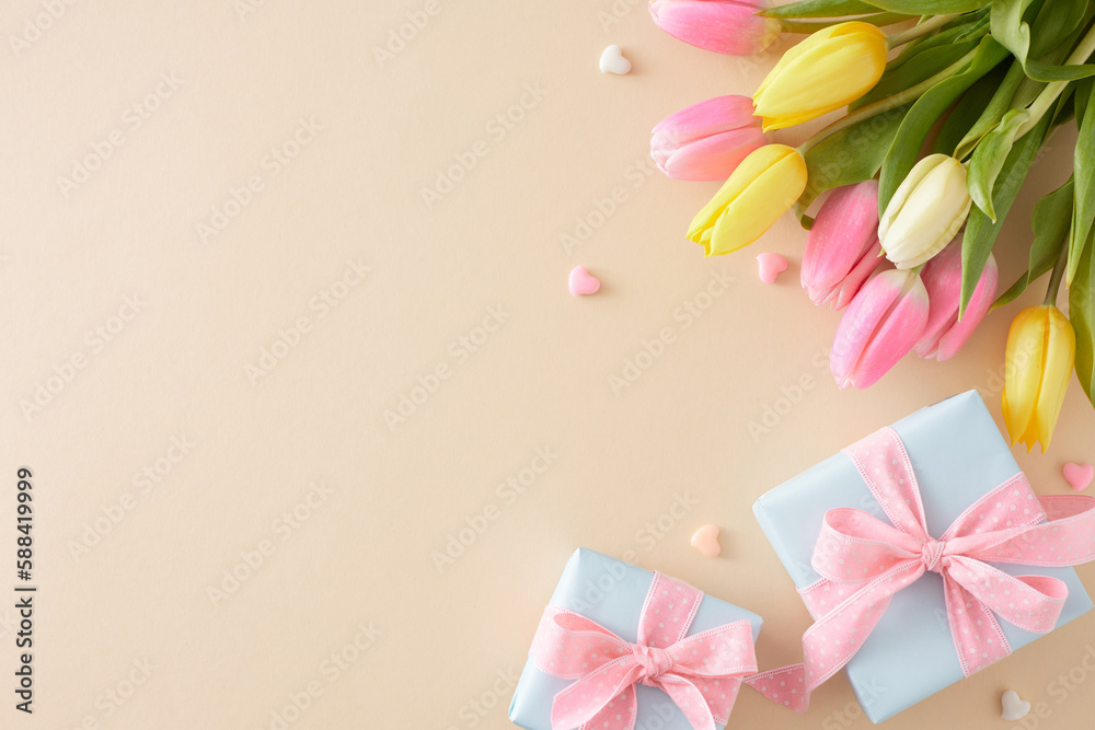 Mother's Day mood concept. Top view composition of present boxes with bows colorful hearts and yellow pink tulips on pastel beige background with empty space