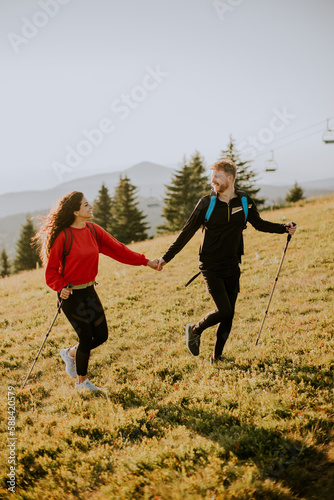 Young couple walking with backpack over green hills