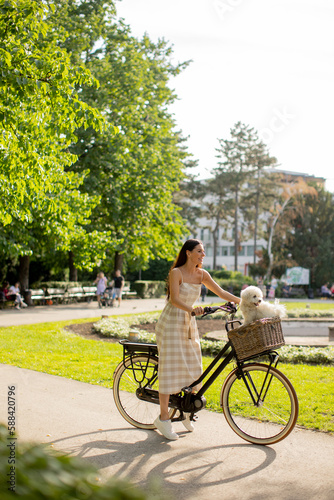 Young woman with white bichon frise dog in the basket of electric bike © BGStock72