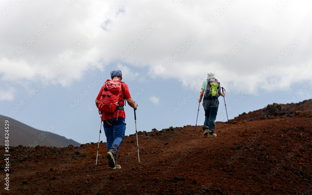 Couple hiking a volcano in tenerife. Hikers with hiking clothing at the mountain. scenic hike