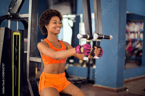 Fitness woman doing exercise on a chest machine fly in a gym. Health and lifestyle concept