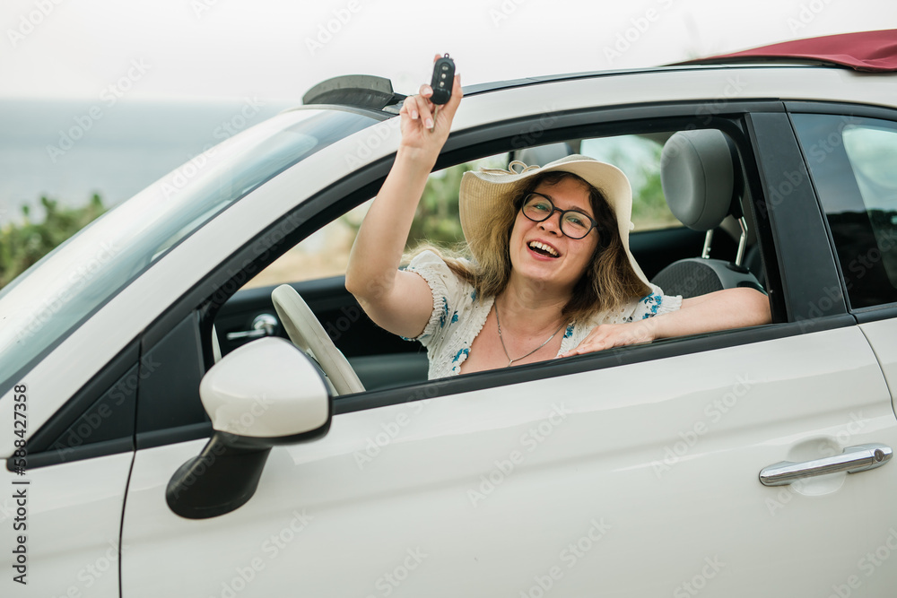 Woman in summer hat driver holding car keys driving her new car cabriolet - automobile and purchase concept Woman in summer hat driver holding car keys driving her new car cabriolet - automobile and purchase concept