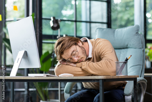 Φωτογραφία Tired programmer, IT specialist fell asleep at the workplace in the office, at home on the table in front of the computer