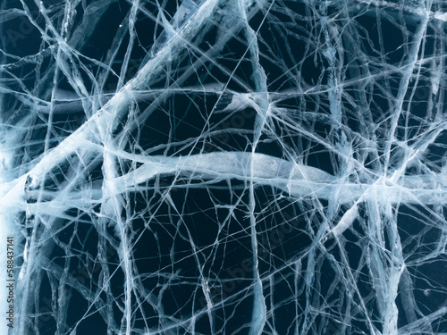 The natural texture of winter ice with white bubbles and cracks on a frozen lake. Abstract background of ice and cracks on the surface of frozen Lake Baikal