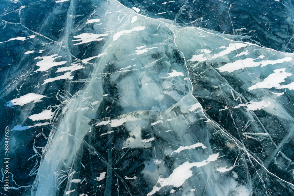 Obraz premium The natural texture of winter ice with white bubbles and cracks on a frozen lake. Abstract background of ice and cracks on the surface of frozen Lake Baikal