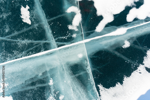 The natural texture of winter ice with white bubbles and cracks on a frozen lake. Abstract background of ice and cracks on the surface of frozen Lake Baikal