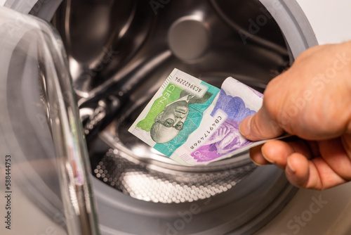 Colombian pesos being thrown into the washing machine, Concept, Money laundering, illegal activity, black market, Criminal activity in Colombia
