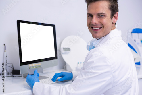 Portrait of dentist working on computer against wall
