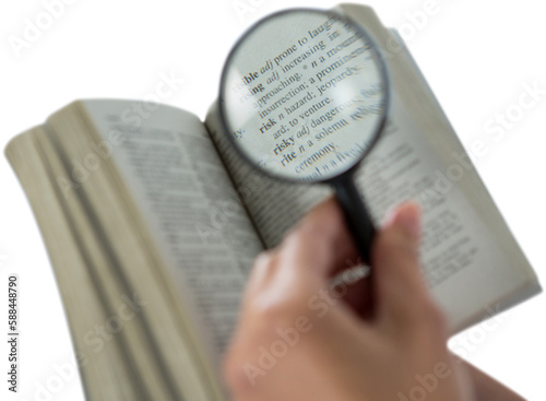 Businesswoman reading dictionary through magnifying glass