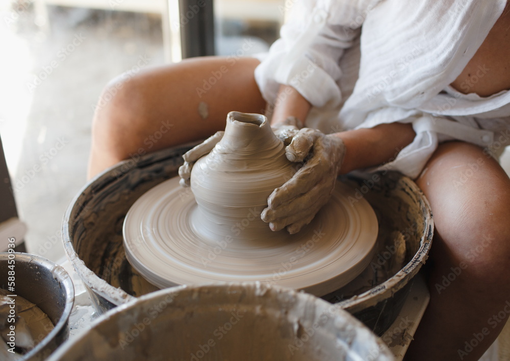 A young ceramist woman sits behind a potter's wheel, Handicraft A young ceramist woman sits behind a potter's wheel, Handicraft