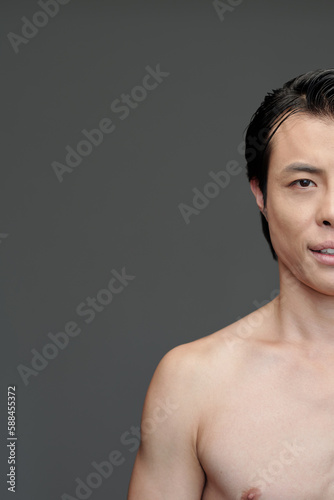 Portrait of shirtless fit Asian man smiling at camera