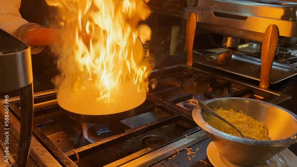 A chef prepares pasta in a fast food style. The frying pan is on fire